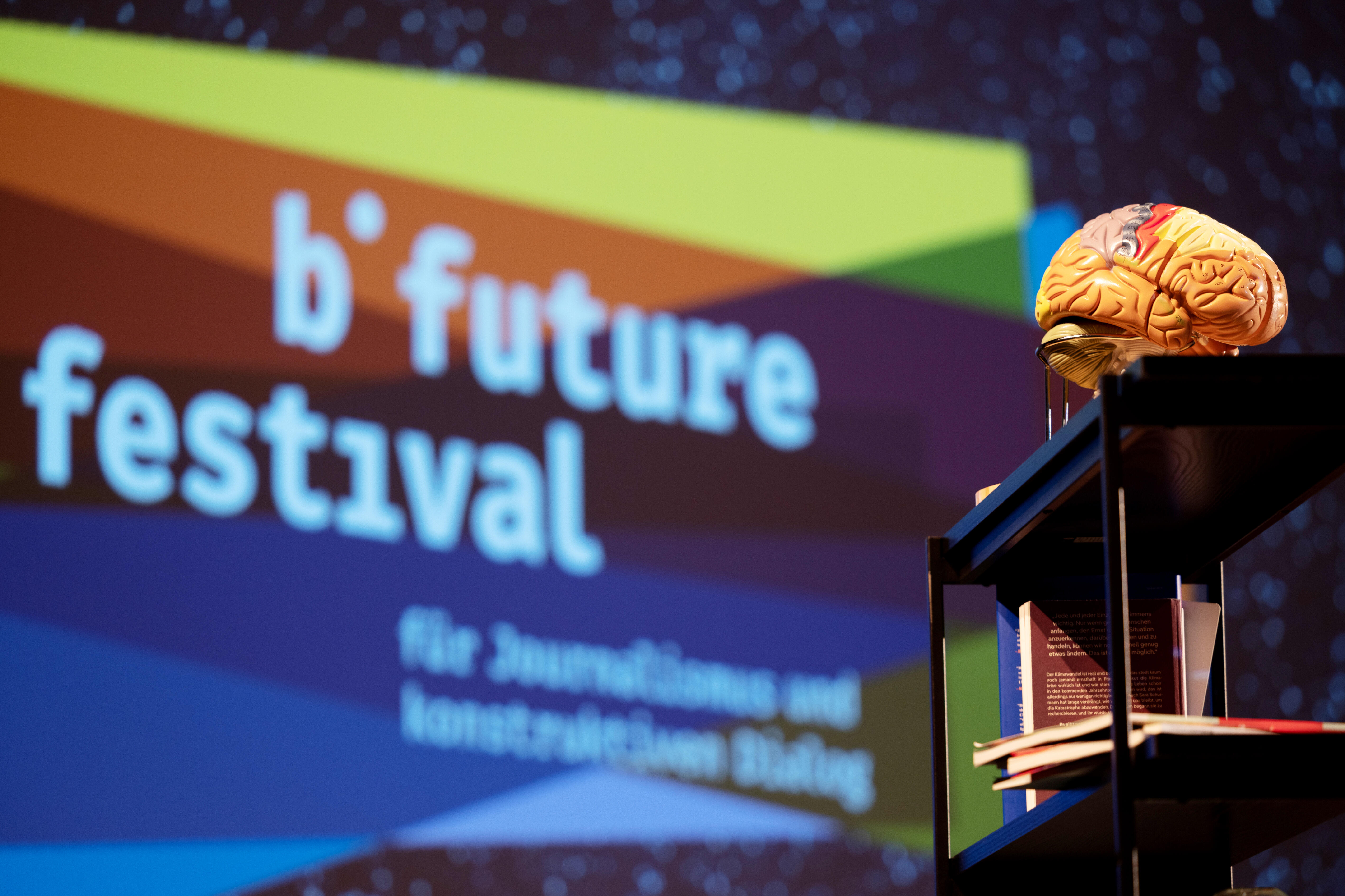 The presentation stage with the logo of the b-future festival in the background. In the foreground, there is a 3D model of a human brain.