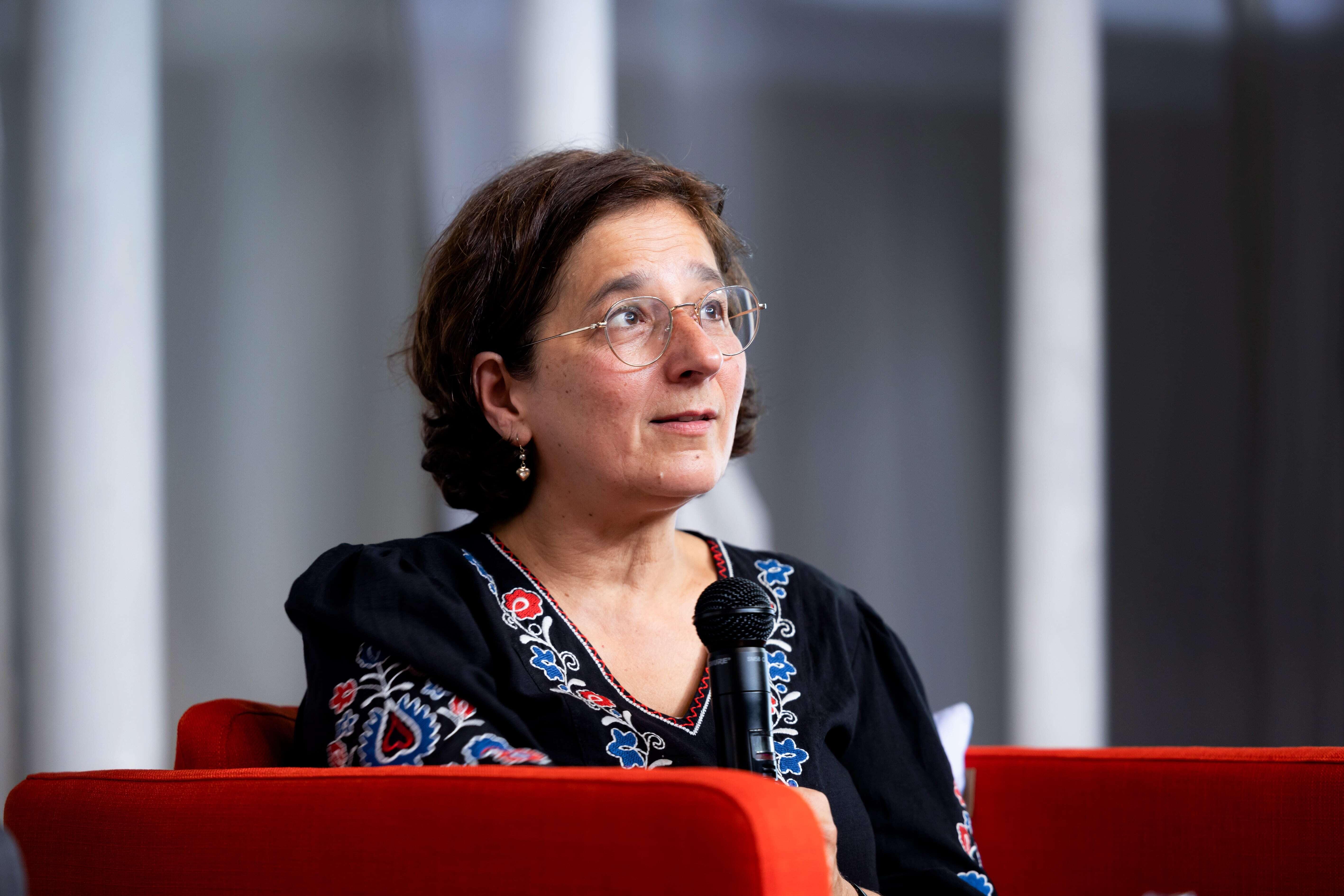 Isabel Schayani sitzt auf einem roten Sessel und spricht ins Mikrofon.