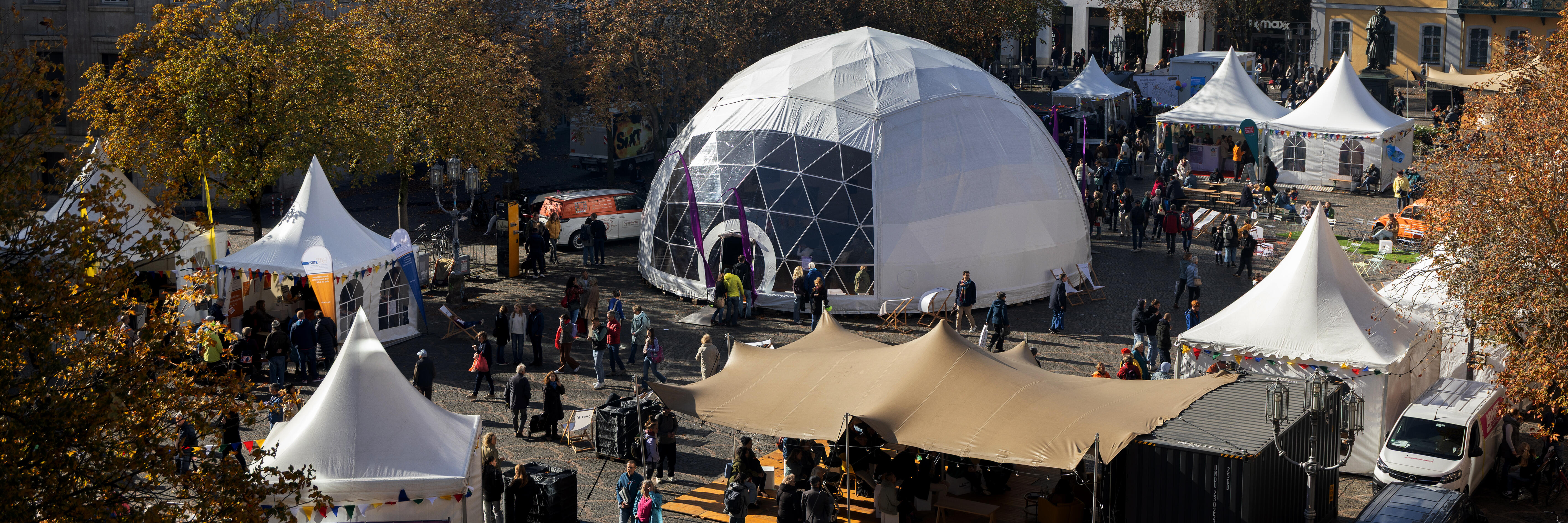 Luftaufnahme vom Münsterplatz in Bonn, mit mehreren Zelten und Menschen.