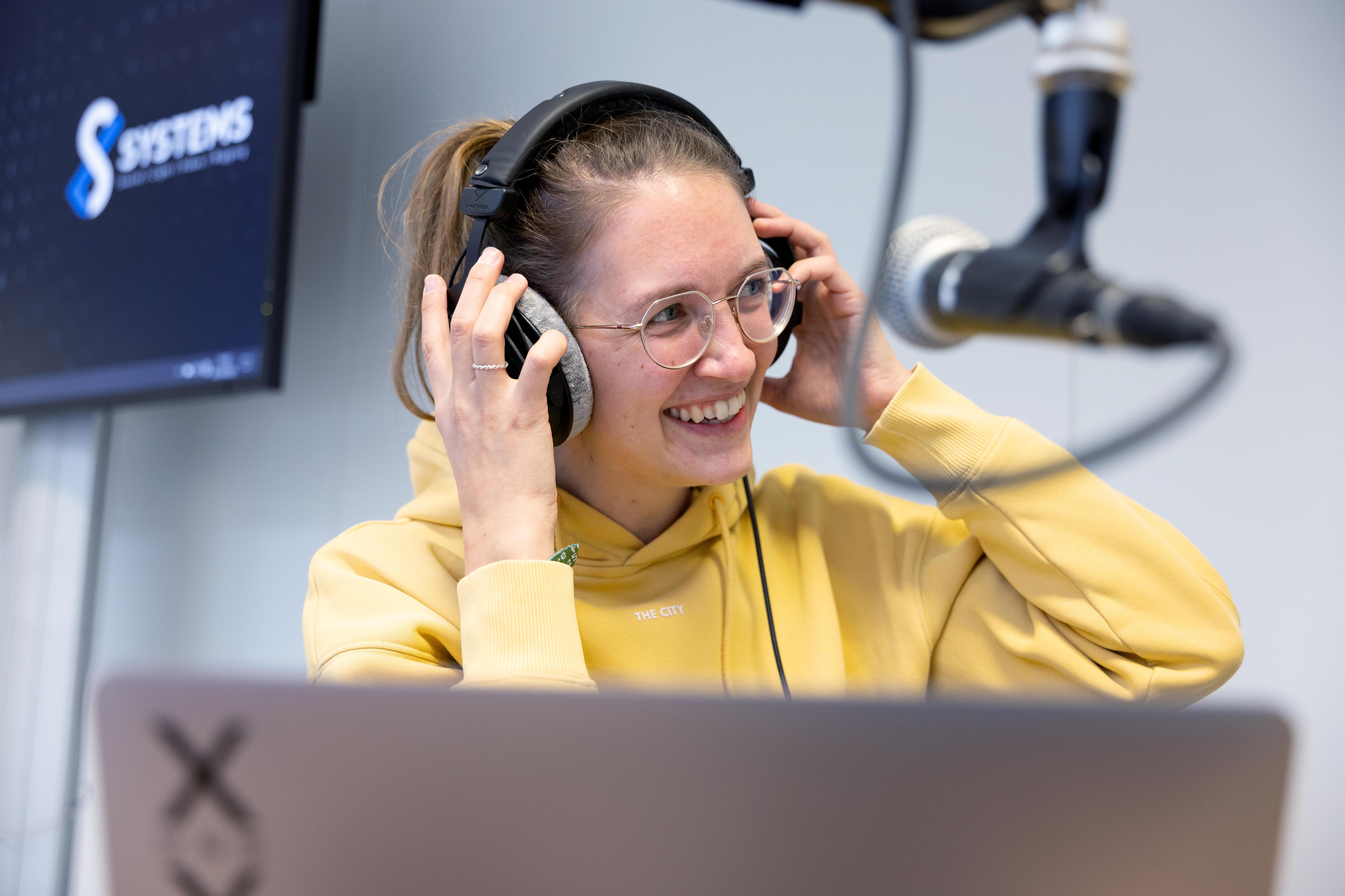 Frau die Podcast aufzeichnet und lacht.