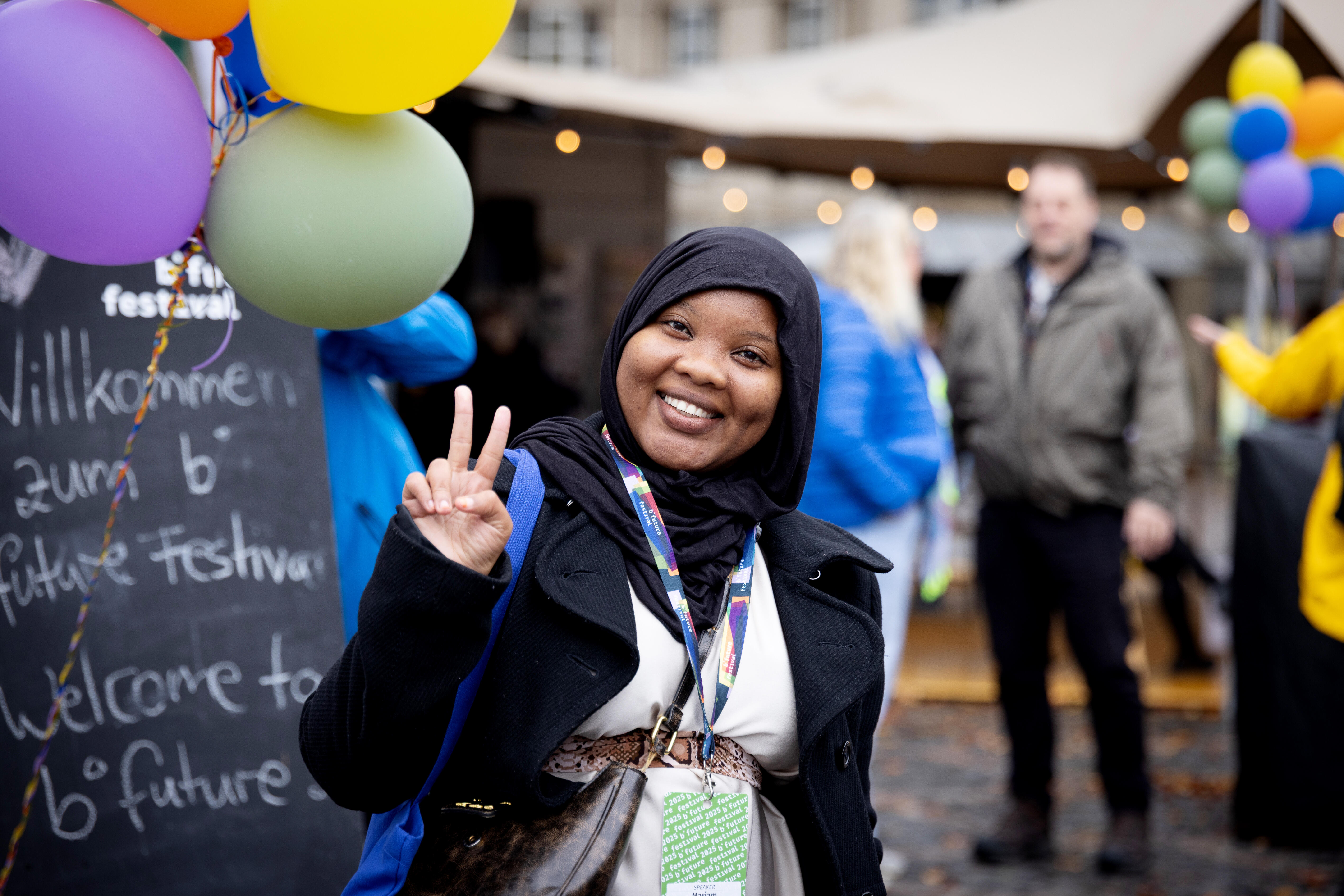 Speakerin Mariam Gichan Athman zeigt das Peace-Zeichen und lächelt in die Kamera
